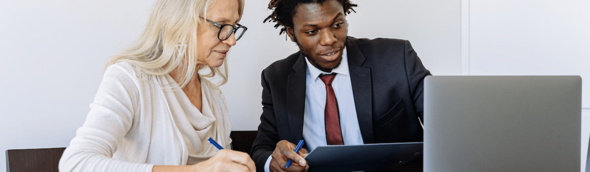 Elderly Woman Looking at her customer journey on a Computer Beside a Man in Black Suit