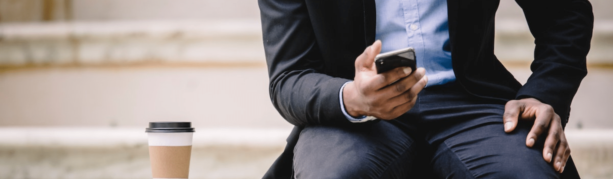 Crop businessman using sms smartphone while resting on bench with takeaway coffee
