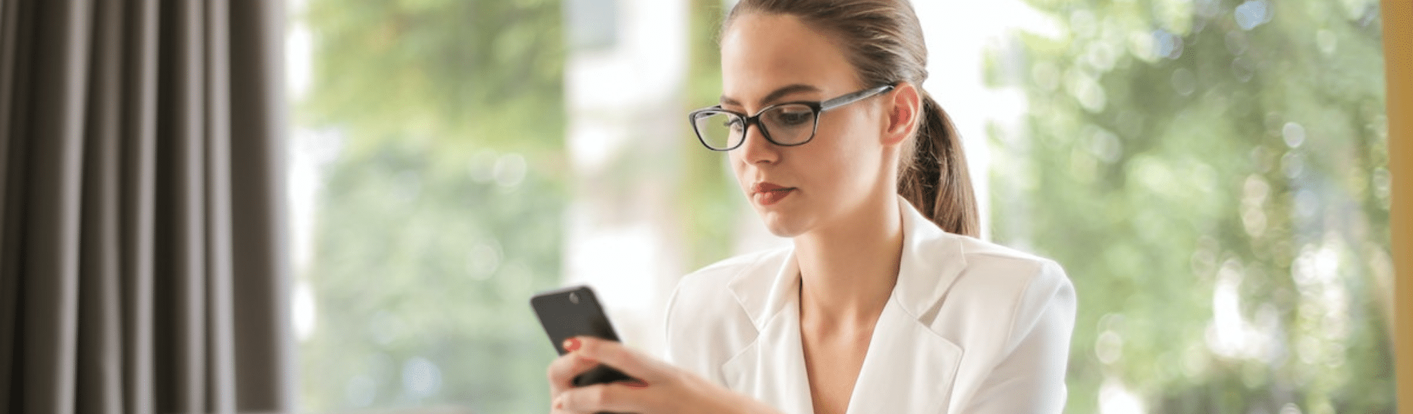 Serious businesswoman using smartphone in workplace
