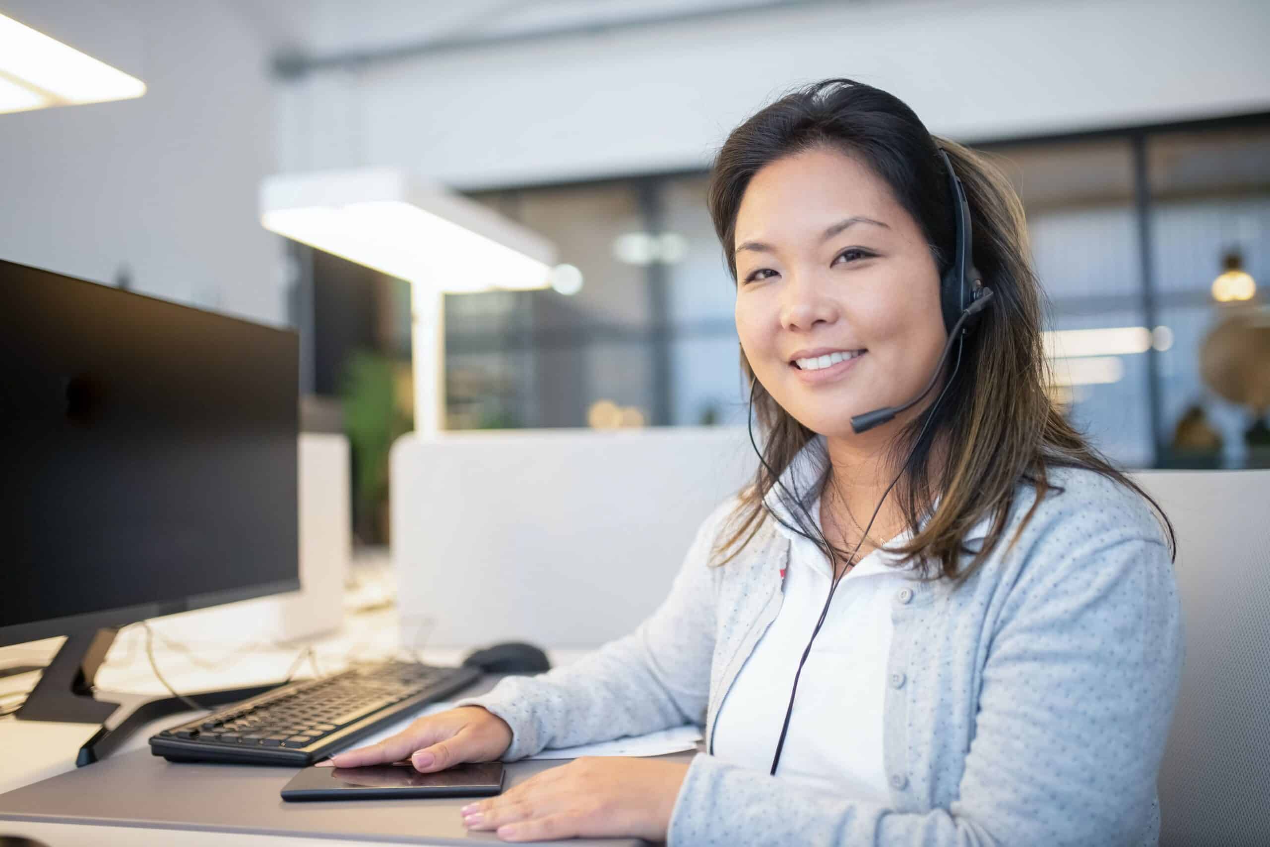 Support agent on the computer looking at the camera smiling