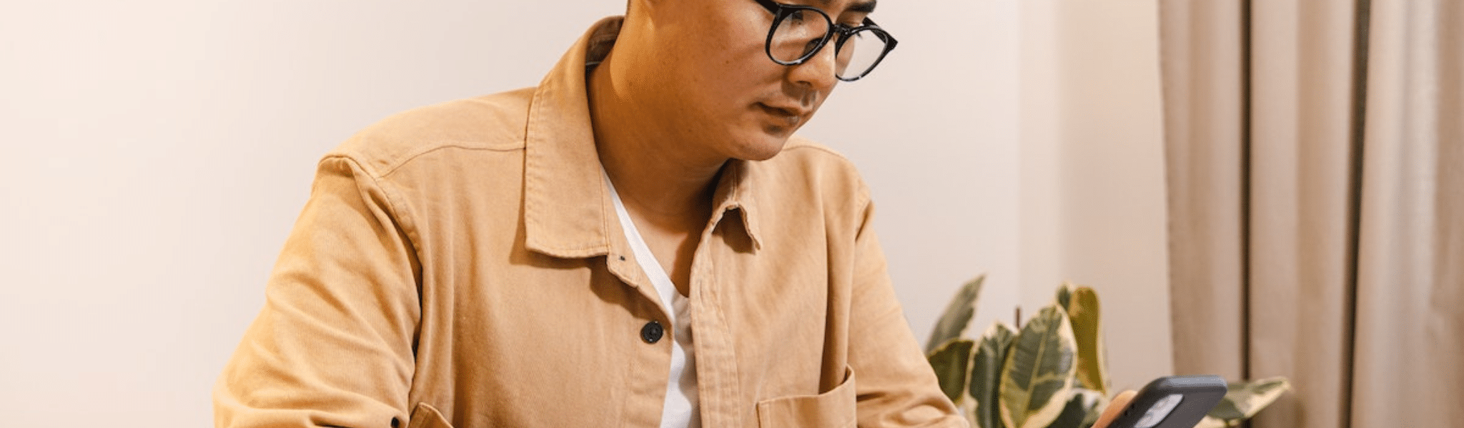 Man Sitting at a Table with a Smart Phone and Notebook
